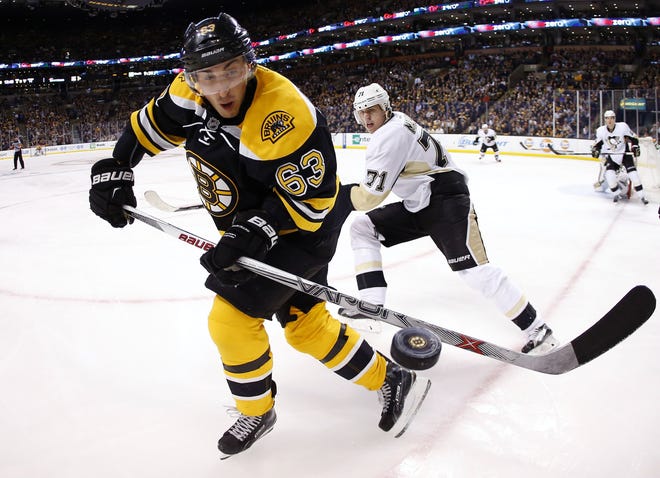 Brad Marchand eyes a loose puck in front of the Penguins' Evgeni Malkin. The Associated Press