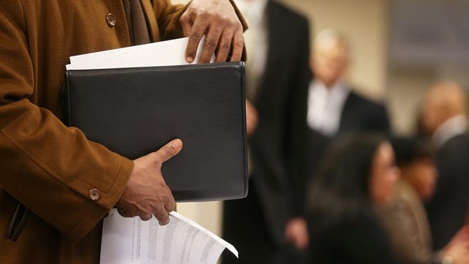 An applicant goes through paperwork at a job fair on Jan. 17, 2013. Palm Beach County’s jobless rate continues to fall, hitting an eight-year low. (Getty Images)
