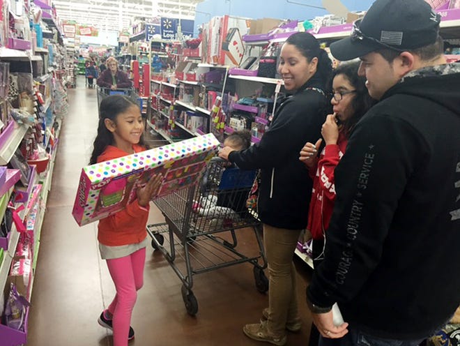 Alani Medina, 8, shows a children's nail kit to her parents and sisters during "Santa Lamm" event Saturday morning at Wal-Mart in Arlington.