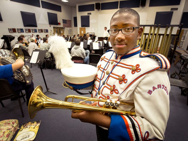 In this Thursday, Dec. 10 2015 photo, Raeshaun Potts poses for a photo with his trumpet and in his band uniform during band practice at Bartow High School in Bartow, Fla. Even though a birth defect left Potts with two prosthetic legs, he remained undaunted in his determination to stand shoulder to shoulder with his fellow marching band members.