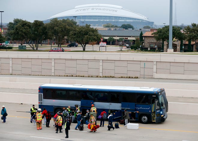 Arlington firefighters and police officers assist passengers with their luggage after the Greyhound bus struck a stalled SUV in the fast lane on westbound Interstate 30 near Collins St. in Arlington, Texas, early Sunday, Dec. 20, 2015. (Tom Fox/The Dallas Morning News via AP)