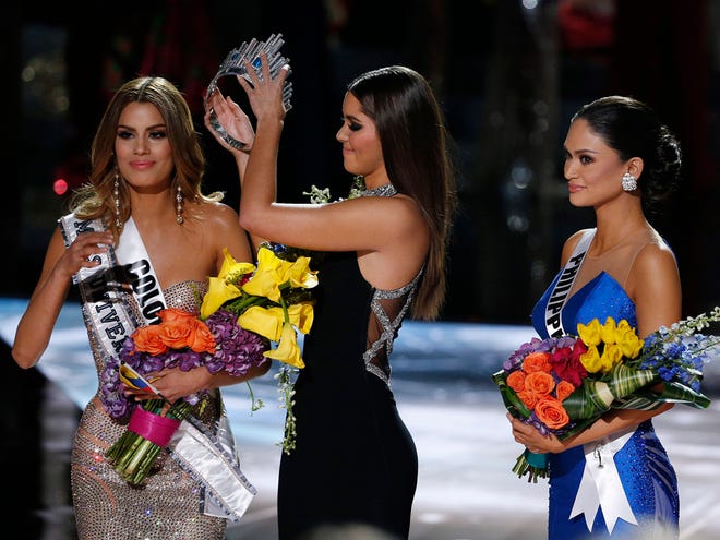 Former Miss Universe Paulina Vega, center, removes the crown from Miss Colombia Ariadna Gutierrez, left, before giving it to Miss Philippines Pia Alonzo Wurtzbach, right, at the Miss Universe pageant on Sunday in Las Vegas.