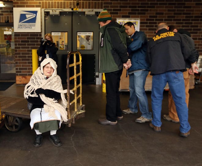Protester Peg Morton (left) sits on a mail dolly as she waits for her turn to be arrested by Postal Police for occupying and refusing to leave a loading dock at the Postal Processing Center in Springfield, Ore. on Monday, Dec. 16, 2013. Eight people were arrested protesting the possible closure of the Springfield Postal Center. (Chris Pietsch/The Register-Guard)