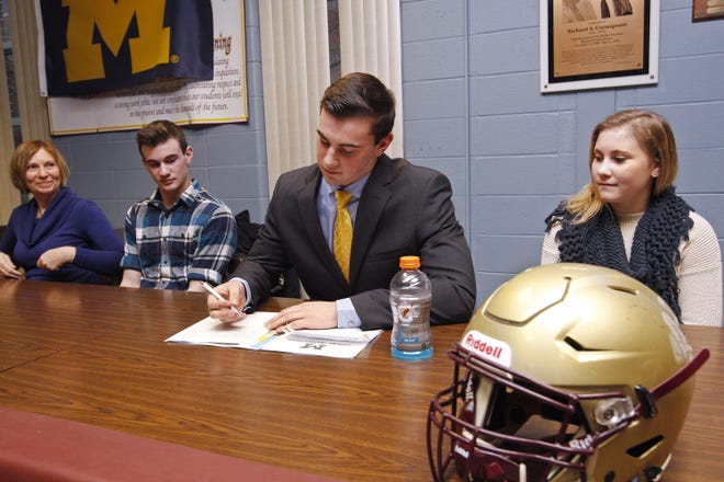 Shepherd Hill Regional High senior tight end Sean McKeon of Charlton signs his letter of intent for the University of Michigan football program Tuesday. Looking on from left is Sean's mother Charlotte McKeon, brother Brendan, 16, and sister Erin, 14. Matthew Healey photo