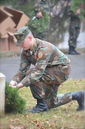 A member of the Ionia County Young Marines places a wreath on the grave of a veteran. The group participated in the ceremony earlier in the month and attended Operation Handshake on Wednesday afternoon.