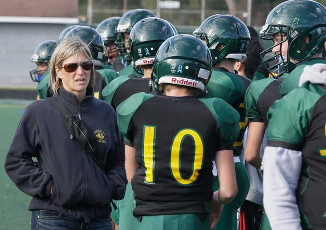 In this Oct. 1, 2015, photo, Birmingham Groves athletic trainer Kelly Salter walks on the sidelines during a freshman football game in Beverly Hills, Mich. Salter attends all of the high school sporting events and administers assessment tests to athletes who suffer concussions. Groves is one of 62 Michigan high schools participating in a unique pilot concussion program that does baseline testing of athletes in football and other sports. (AP Photo/Carlos Osorio)