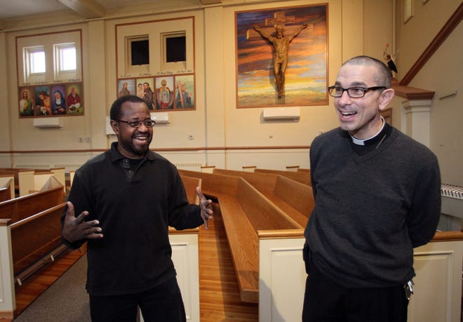 Artist Munir Deishinni Mohammed, left, and the Rev. James Ruggieri, pastor of St. Patrick Church in Providence, talk about the muralist's wall portraits. The Providence Journal/Mary Murphy