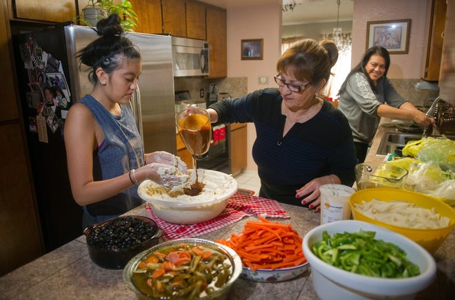 Amanda Castro, a 17-year-old Franklin High senior, left, is helped by her aunt, Teresa Hidalgo, in making masa for tamales, as Amanda's mother, Anna Castro, prepares chilies at Hidalgo's home in Stockton. CLIFFORD OTO/THE RECORD