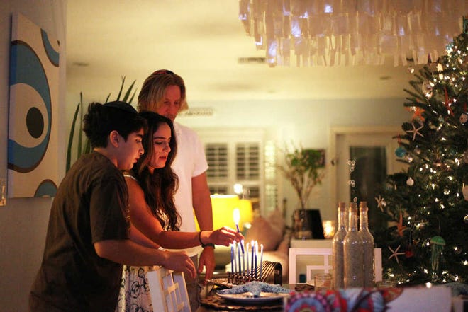 Shelly Tygielski, 37, lights the menorah with her son Liam Asayag, 13, and husband Jason Tygielski, 50, on Dec. 13, 2015, at their home in Lighthouse Point, Fla. Shelly was raised in an Orthodox Jewish family and Jason in a Catholic home. Although today they identify with Buddhism more than any other religion, they still keep tradition celebrating Hanukkah, Christmas and other religious holidays. (Barbara Corbellini Duarte/Sun Sentinel/TNS)
