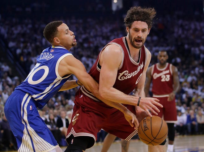 Cleveland Cavaliers forward Kevin Love (0) is defended by Golden State Warriors guard Stephen Curry. left, during the first half of their game Sunday in Oakland, Calif. Photo by AP