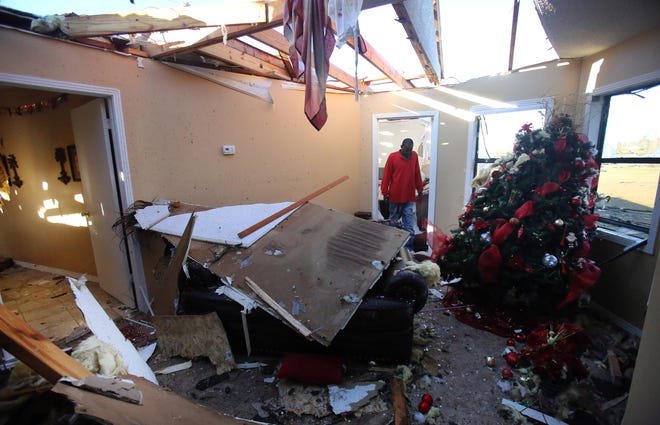 Ladarren Phillips surveys tornado damage to a house on Rising Star Road in Holly Springs, Miss., Thursday, Dec. 24, 2015. At least 11 people were killed in as spring-like storms mixed with unseasonably warm weather and spawned rare Christmastime tornadoes in the U.S. South, officials said Thursday. Emergency officials blamed the severe weather for injuring scores of others and destroying dozens of cars, homes and businesses. (Stan Carroll/The Commercial Appeal via AP)
