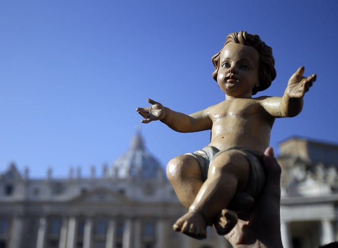 A man holds up a statue of Baby Jesus before the start of the Angelus noon prayer in St. Peter's Square at the Vatican in Rome Dec. 20. GREGORIO BORGIA/THE ASSOCIATED PRESS