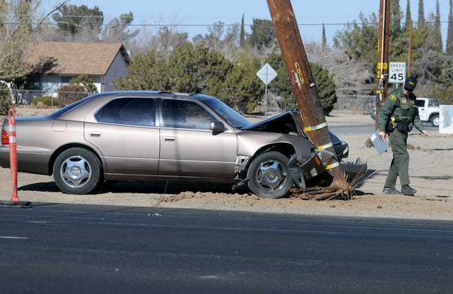 A San Bernardino County Sheriff deputy takes a look at a car which struck a power pole at the intersection of Main Street and Oakwood in Hesperia on Saturday morning. (James Quigg, Daily Press)