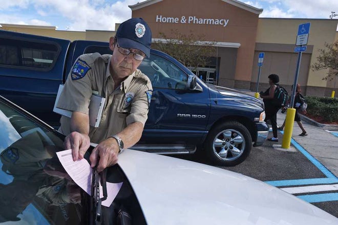 Bob.Self@jacksonville.com Jerry Lepore leaves a citation on the windshield of a vehicle parked in a handicapped space without a pass outside Wal-Mart Supercenter on 103rd Street. Lepore is one of 20 volunteers authorized for the duty.