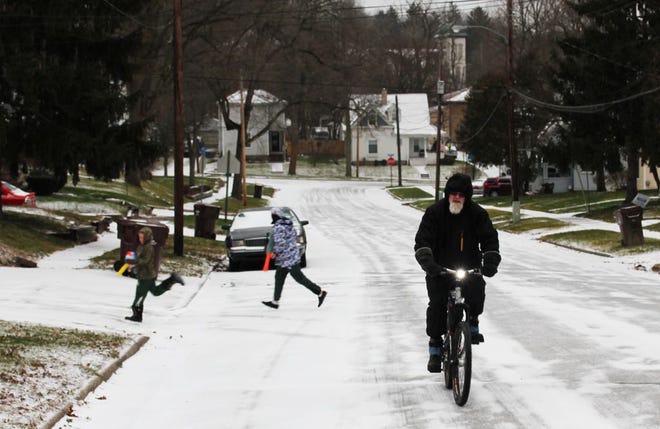 Children play in the snow as Tony Holtrust of Ionia rides a bike before a storm hit Ionia Monday afternoon. 

Nicholas Grenke / Ionia Sentinel-Standard