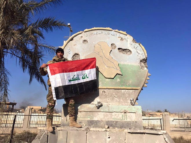 An Iraqi soldier holds a national flag in the government complex in central Ramadi, 70 miles (115 kilometers) west of Baghdad, Iraq, Monday, Dec. 28, 2015.
