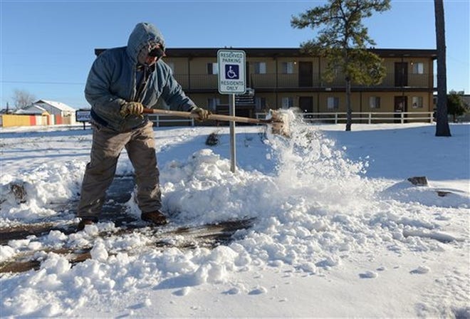 Ismael Avelar, maintenance employee for the Village Place Apartments, shovels snow Monday morning, from the walkway to the apartment complex office in Odessa, Texas. As much as 7 inches of snow fell over the weekend in Odessa and many businesses and government offices were closed Monday. Avelar said he slid or became stuck four times while driving to work. MARK STERKEL/ODESSA AMERICAN via AP