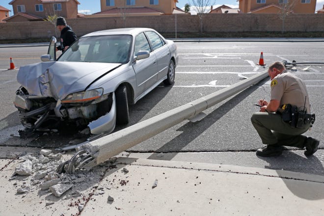 A San Bernardino County sheriff's deputy investigates at the scene of a crash on Bear Valley Road at San Dimas Street in Victorville on Monday. No injuries were reported when the car hit a light pole. Gabriel Preciado, for the Daily Press