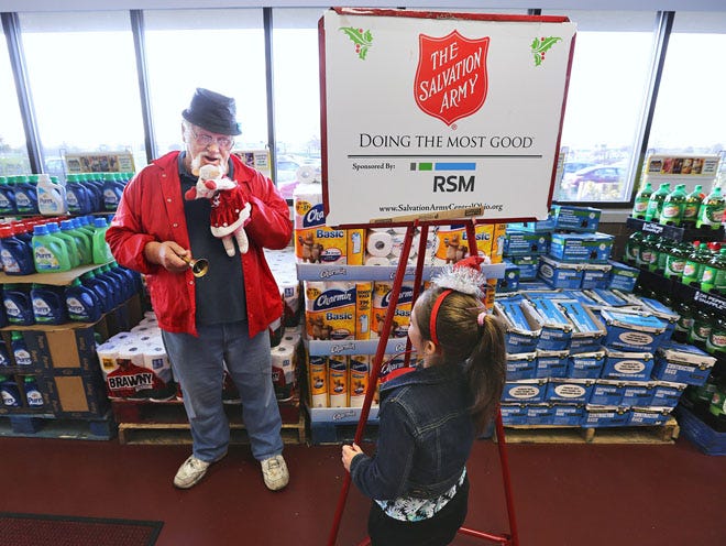 Robert Geary thanks a young donor while ringing his brass bell for the Salvation Army and holding a Lamb Chop puppet. Geary was working Tuesday at the entrance of the Anderson's store on the North Side, near Dublin.