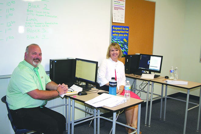 Bob Crider and Christine Reiber, school administrators, sit at desks used by students at Academy for Character Education.
