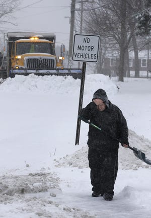 Corey Nachman of Portsmouth, N.H., holds his hand to his face while shoveling his driveway Tuesday. Highway speeds were limited in New Hampshire where more snow was expected. Steven Senne/The Associated Press