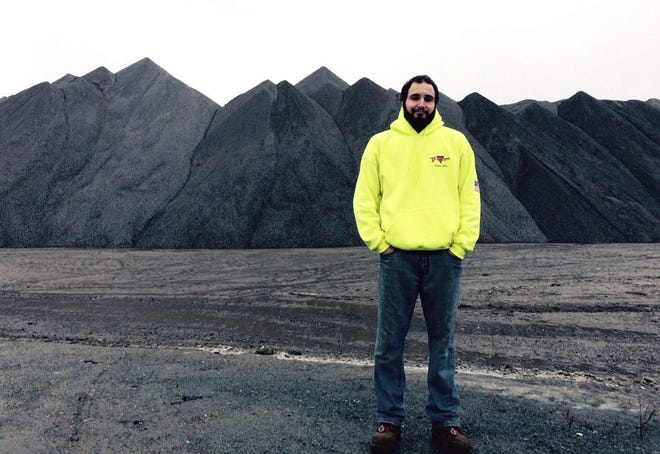 Christopher Trudelle of Podgurski Corp. of Canton stands in front of a veritable mountain of rock salt totaling 53,000 tons at the Taunton salt yard on Cushman Street.