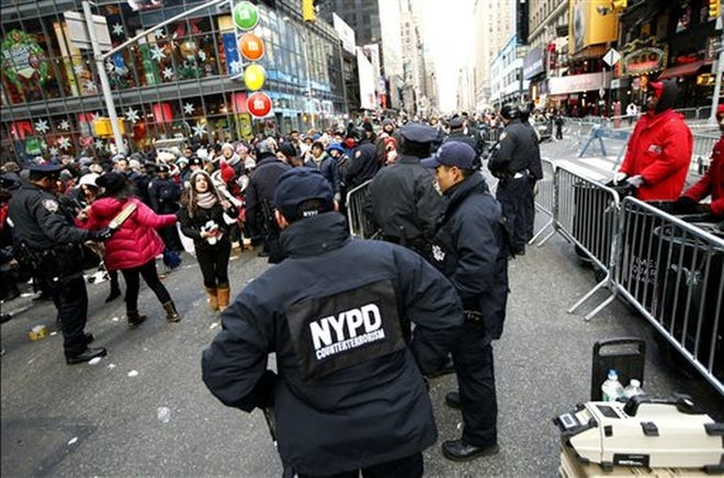 In this Dec. 31, 2104 file photo, counterterrorism officers, foreground, armed with an explosives detection device, far right, watch as other police officers inspect revelers entering a cordoned off area in Times Square in New York, on New Yearís Eve. New York City officials seek to assure potential revelers that Times Square will be one the safest places in the world on New Year's Eve 2015. AP FILE PHOTO