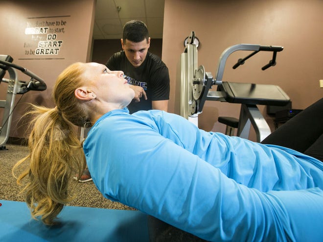 Kristin Catich works on a floor exercise with the help of trainer Ray Castro at Zone Health and Fitness in Ocala on Tuesday.