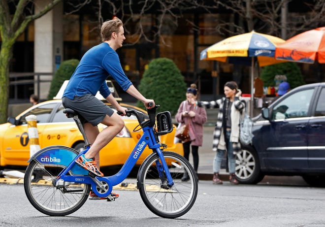 FILE - In this Dec. 24, 2015 file photo, a man wearing shorts, sneakers and no socks rides a rental bike through a downtown Manhattan street on Christmas Eve in New York, as temperatures climbed into the 70's. An unseasonably mild December shattered temperature records across the Northeast. The National Weather Service said as of Wednesday, Dec. 30, 2015, the average temperature in Boston for the month was nearly 11 degrees above normal. New York, Burlington, Vt., Concord, N.H., and Portland, Maine, were all well above average. (AP Photo/Kathy Willens, File)