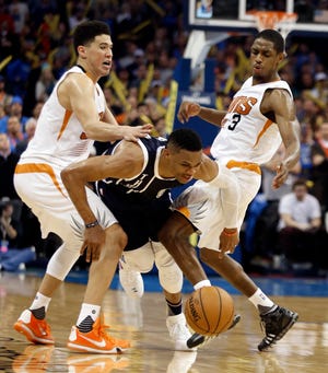 Oklahoma City Thunder's Russell Westbrook (0) is fouled as he splits defenders Phoenix Suns' Devin Booker (1) and Brandon Knight (3) during the second half of an NBA basketball game where the Oklahoma City Thunder defeated the Phoenix Suns110-106 at Chesapeake Energy Arena on Dec. 31, 2015 in Oklahoma City, Okla. Photo by Steve Sisney, The Oklahoman
