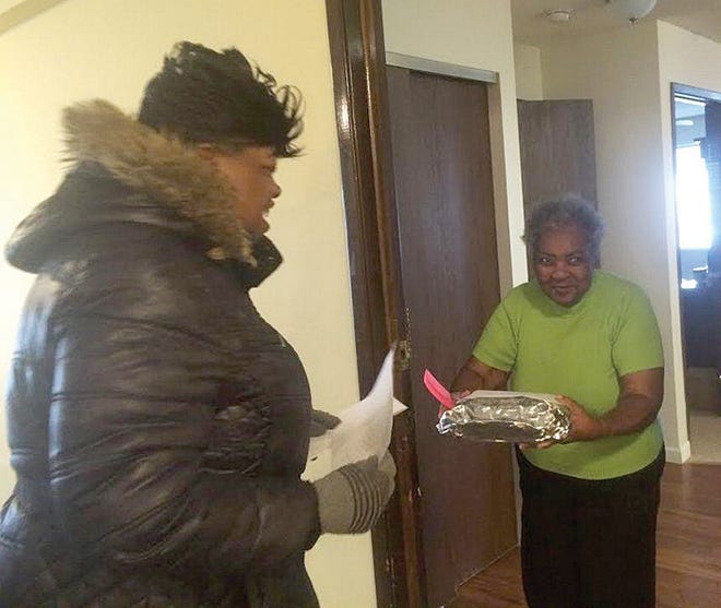Charlean Bell (right) of Peoria accepts a freshly cooked meal from Wendy Riddle on New Year's Day, part of the annual Central Illinois Holiday Meals Project. Bell's meal — turkey roll, mashed potatoes, green beans, a dinner roll and cake — were cooked and packaged at Bethel United Methodist Church in Peoria, one of four churches that partnered with the Central Illinois Agency on Aging to cook and deliver 800 meals in Peoria and Tazewell counties.
