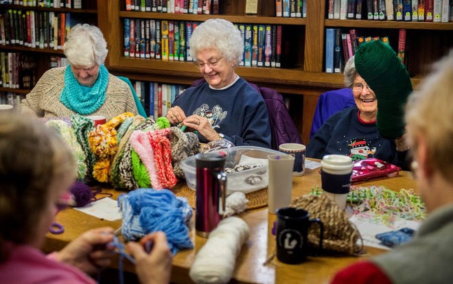 Joyce Culbertson, back left, and Janice Allgood knit as Barb Day laughs, showing her yarn roll that looks like a pickle. The Cro-Knits group gathers ever week at the Ayer Public Library in Delavan, making more than 1,000 stocking hats and other items that they have donated to groups across the country over the past three years. The group gets by on donated yarn and is hoping for more donations to sustain their efforts.