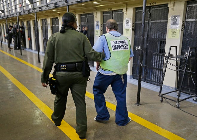 In this photo taken on Tuesday, Dec. 29, 2015, a hearing impaired condemned inmate is escorted back to his cell on death row at San Quentin State Prison in San Quentin, Calif. With California's lethal injection protocol in limbo, the nearly 750 inmates at San Quentin State Prison, the nation’s most populous death row, are more likely to die from natural causes or suicide than execution. The inmates await a final decision on a proposed one-drug execution method and the possibility that voters in 2016 will scrap the death penalty altogether.