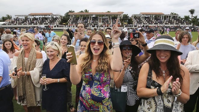 Gina Skelton (center) of Delray Beach and others cheer as the band The London Essentials play on the field during halftime of the Herbie Pennell Memorial Cup tournament final at International Polo Club Palm Beach in Wellington Sunday, January 3, 2016. (Bruce R. Bennett / The Palm Beach Post))