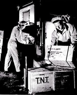 Image from "National Fireworks Review" book, 1940s: Melting TNT, a yellowish powder, used in making amatol. Workers wear coveralls and paper caps for protection against TNT dust.