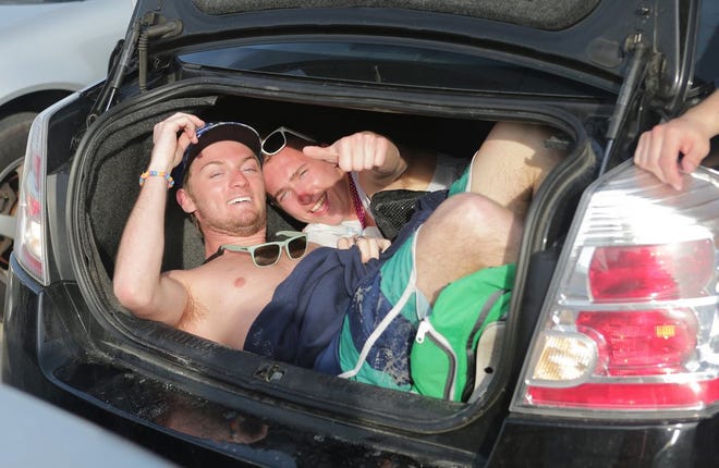 Two spring breakers crowd into a car trunk in March 2015. Tourism and county officials are looking to tame the annual party.