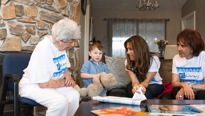 From left, Dorothy Adler of South Palm Beach; Ethan Frost, 3, with his new book; Amy Bergman, director of Jewish Family Life, and Sheila Engelstein of Palm Beach. The book was delivered to Frosts’ Wellington home by Adler and Engelstein, donors to PJ Library. (Courtesy of Friedman Commission for Jewish Education of the Palm Beaches)