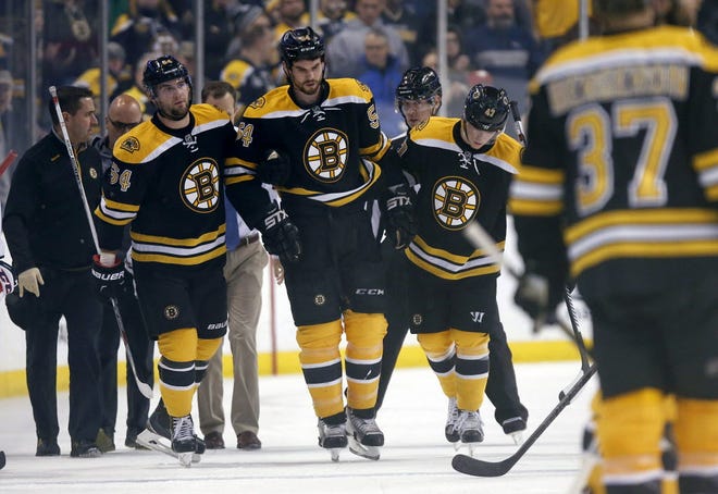 Boston's Adam McQuaid (54) is helped off the ice after a hit by Washington's Zach Sill.