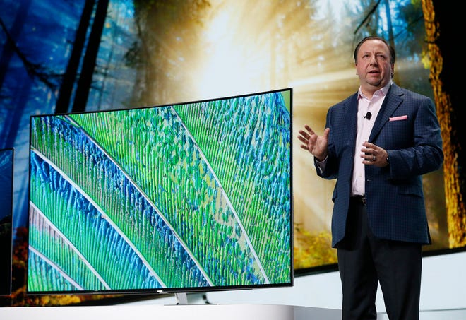 Joe Stinziano, executive vice president of Samsung Electronics America, stands next to Samsung SUHD TVs during a Samsung news conference at CES Press Day at CES International, Tuesday, Jan. 5, 2016, in Las Vegas. (AP Photo/John Locher)