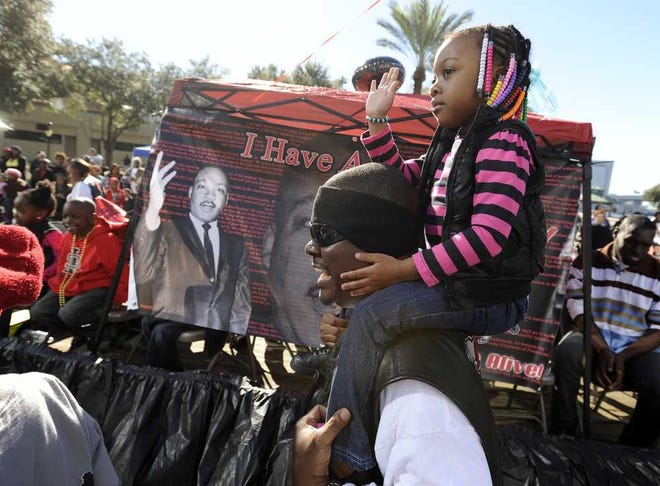 Bob.Self@jacksonville.com Alana Gourgue, 4, rides atop her father Jack Gourgue's shoulders as they take part in the Martin Luther King Jr. Parade in downtown Jacksonville in 2014.