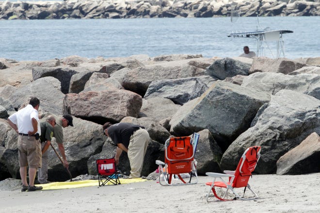 Authorities investigate on July 11, 2015 a blast that threw a beachgoer into a nearby jetty at Salty Brine beach in Narragansett, R.I. Scientists determined that the explosion was probably caused by the combustion of hydrogen that had built up around the cable. (Steve Szydlowski/Providence Journal via AP, File)