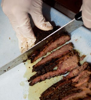 Darryl Lewis cuts slices of beef brisket Wednesday at Lutz’s BBQ, 200 E. Nifong Blvd.
