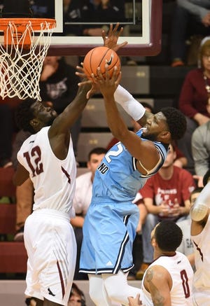 URI's Hassan Martin tries to force a shot despite the pressure from St. Joe's Papa Ndao in first-half action on Sunday. Martin sank the shot and was fouled on the play.