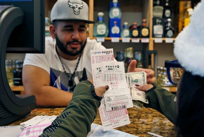 Samir Akhter, the owner of Penn Branch Liquor, exchanges money for Powerball tickets, on Saturday, Jan. 9, 2016, in Washington. No one picked Saturday night's winning numbers, so Wednesday drawing will be worth more than a billion dollars.