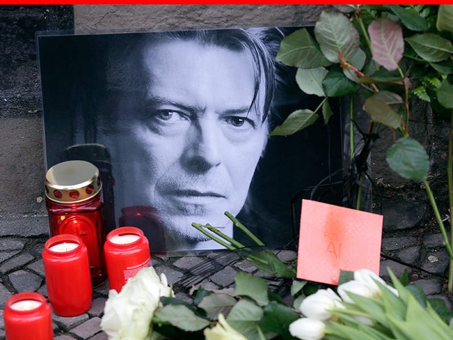 Flowers and a portrait are placed in front of the apartment building where David Bowie once lived in Berlin, Germany, Monday, Jan. 11, 2016, to honor the British musician. Bowie, the innovative and iconic singer whose illustrious career lasted five decades with hits like "Fame," ''Heroes" and "Let's Dance," died Sunday after a battle with cancer. He was 69. (AP Photo/Michael Sohn)