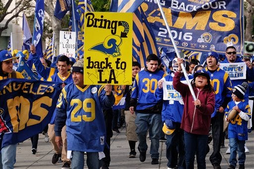 Rams football fans hold banners, wave signs and chant while marching around the historic Los Angeles Memorial Coliseum. Saturday, Jan. 9, 2016 in Los Angeles. Boisterous Los Angeles Rams fans gathered Saturday to herald the NFL football team's possibly imminent return to Southern California after a 21-year sojourn in St. Louis. (AP Photo/Richard Vogel)