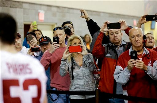 Fans take pictures as the team from Alabama leaves after media day for the NCAA College Football Playoff National Championship in Phoenix, Saturday, Jan. 9, 2016. Alabama will face Clemson in Monday's game. (AP Photo/David J. Phillip)