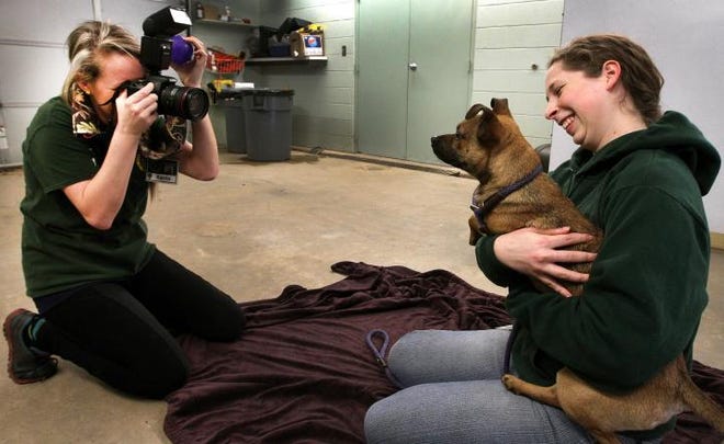 (John Clark/The Gaston Gazette) Volunteer Shannon Rettberg, right, holds "Cody", one of the dogs available for adoption at the Gaston County Animal Care and Enforcement in Dallas as volunteer Karrie Brotzman takes a photo.