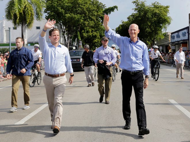Gov. Rick Scott, right, and Lt. Gov. of Florida Carlos Lopez-Cantera, left, wave at participants during the Three Kings' parade Sunday in Miami.