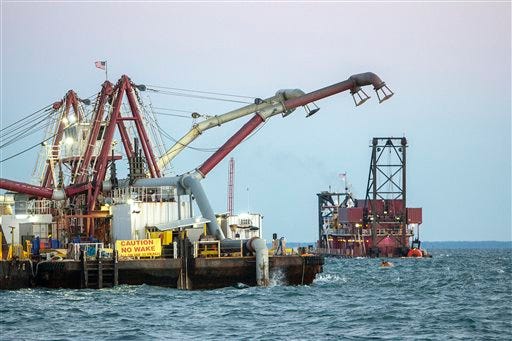The Great Lakes Dredge and Dock spider barge, left, is loaded by the dredge Alaska, right, as it deepens the shipping channel to the port of Savannah off the coast of Tybee Island, Ga., Monday, Sept. 14, 2015. The U.S. Army Corps of Engineers and the Georgia Ports Authority started the dredging the channel five days ago. The $706 million project, first authorized by Congress in 1999, will deepen the shipping channel traveled by cargo ships along 39 miles of the Savannah River. (AP Photo/Stephen B. Morton)